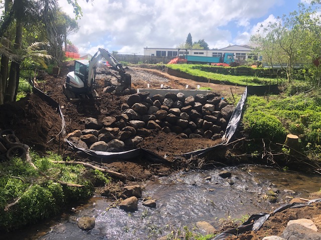 Rock retaining wall being built beside a stream